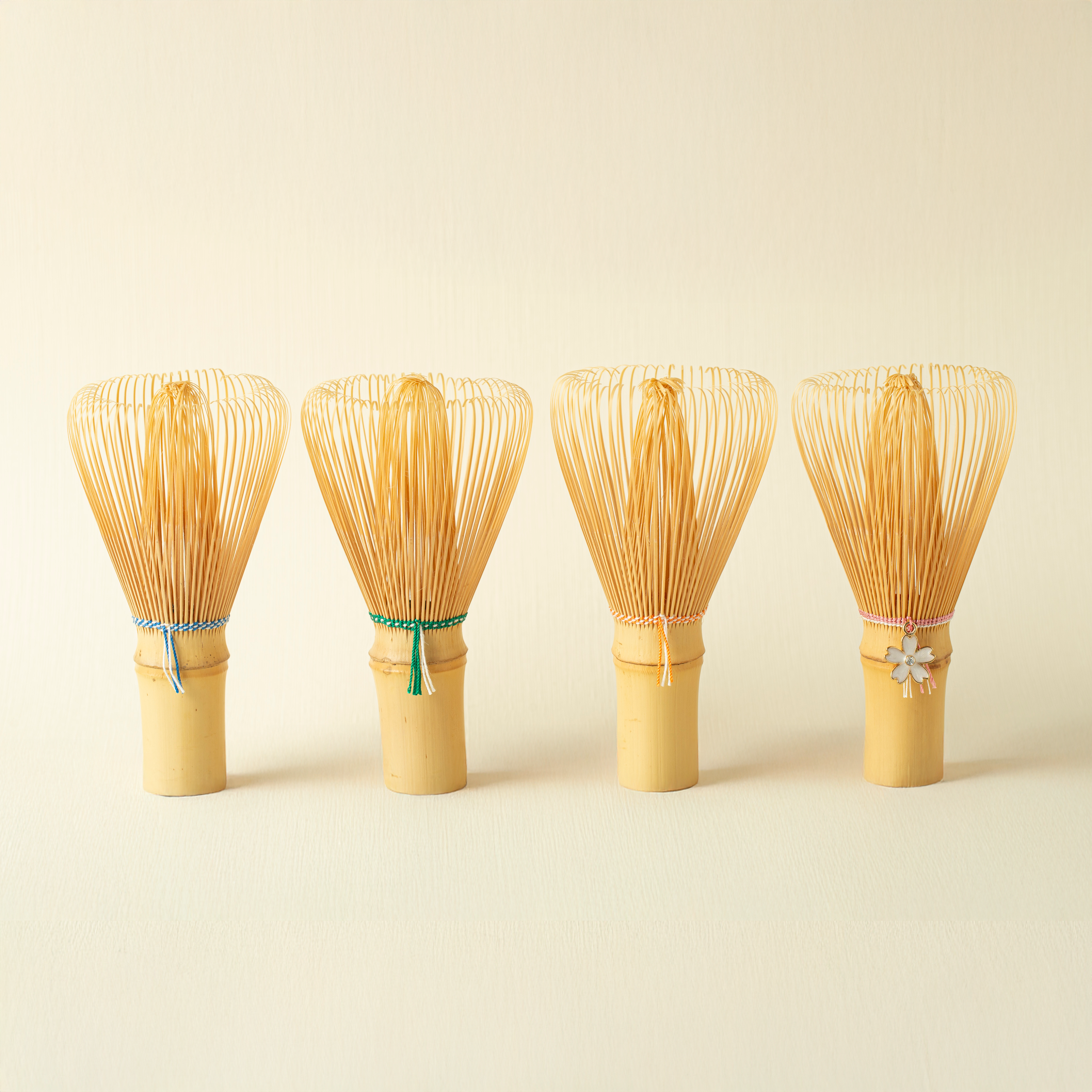 Four bamboo whisk - chasen - on a beige background