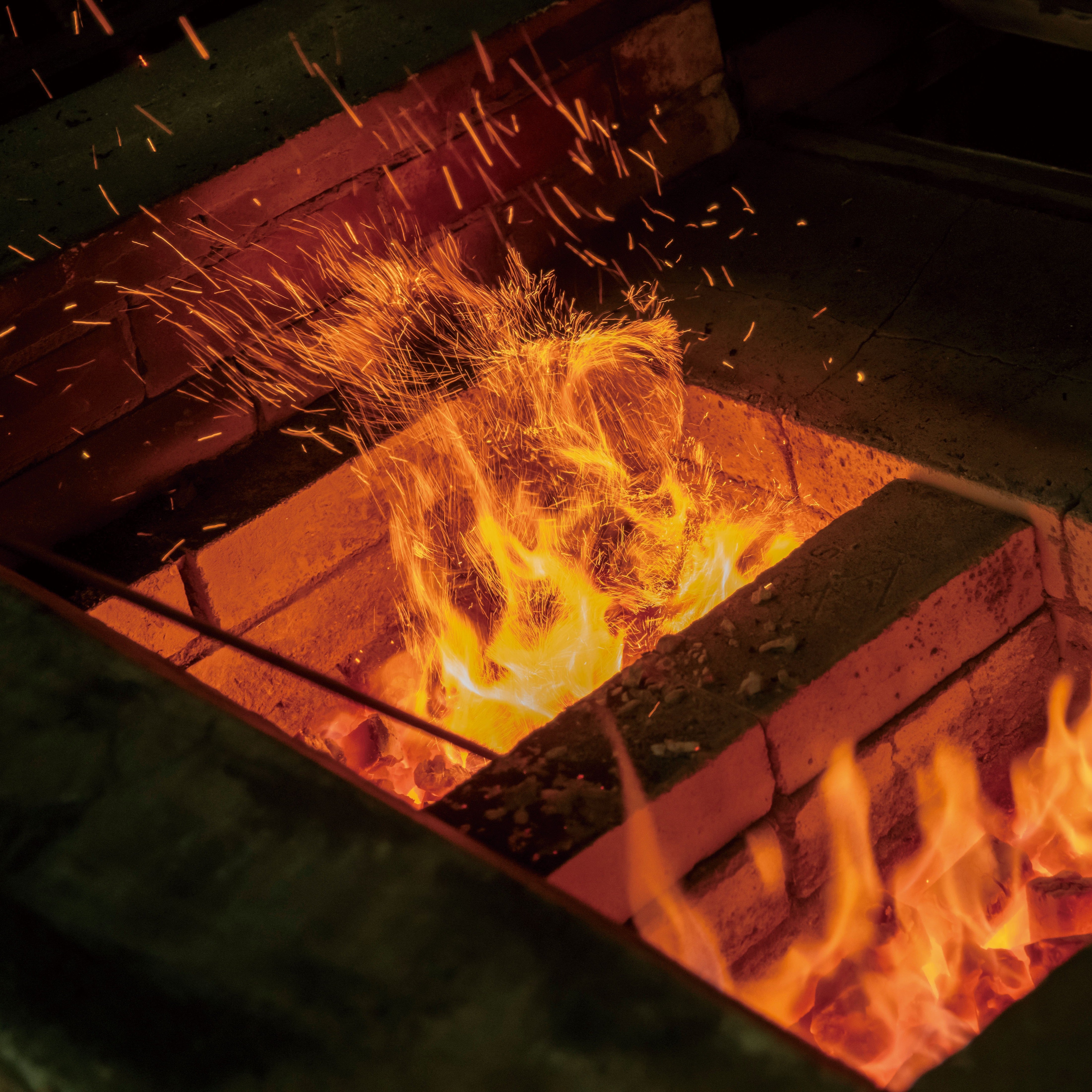 Hot metal glowing red-hot in a forge with sparks flying.