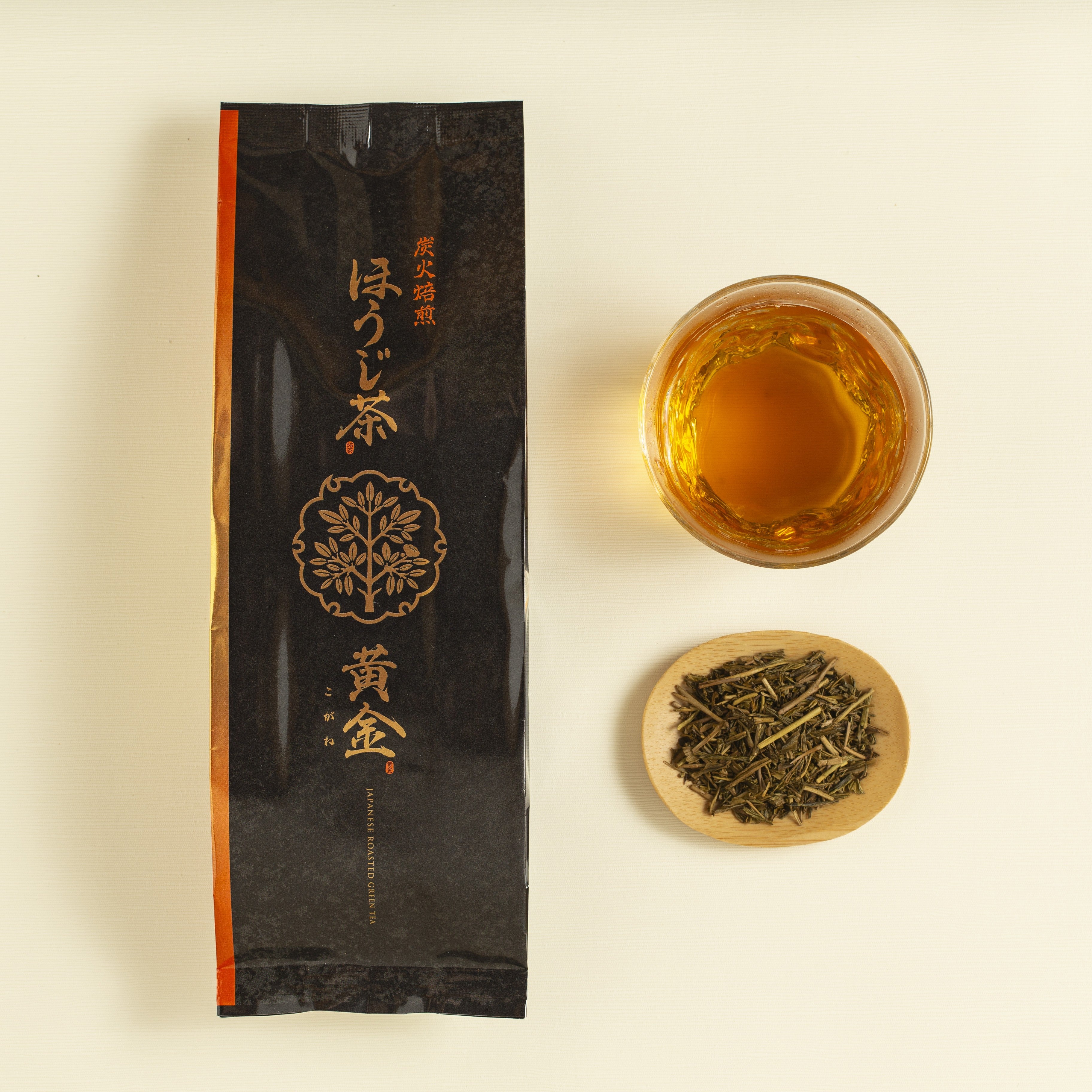 Hojicha packaging with a cup of tea and a bowl of loose tea leaves on a beige background