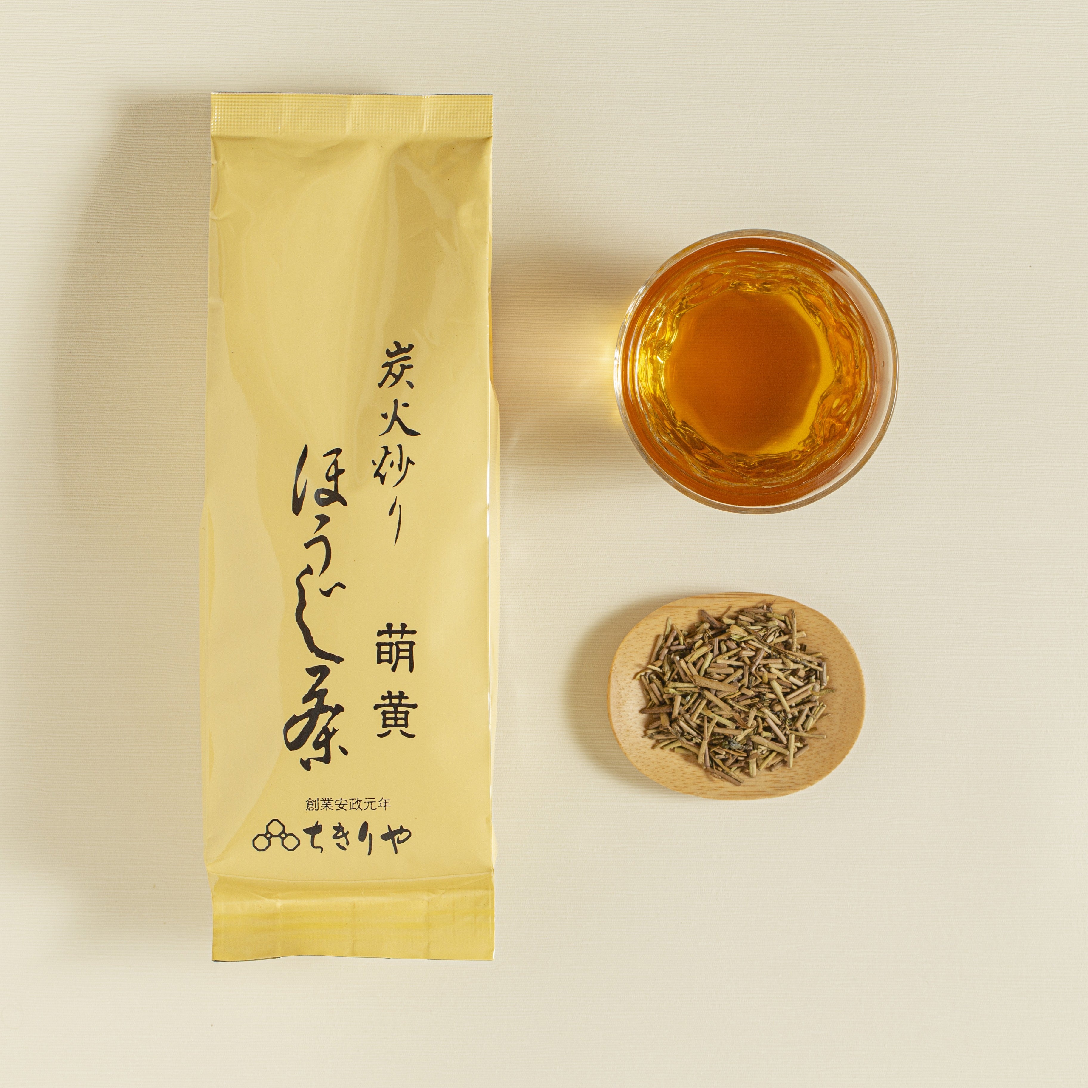 Tea packaging with a glass of tea and a bowl of tea leaves on a beige background