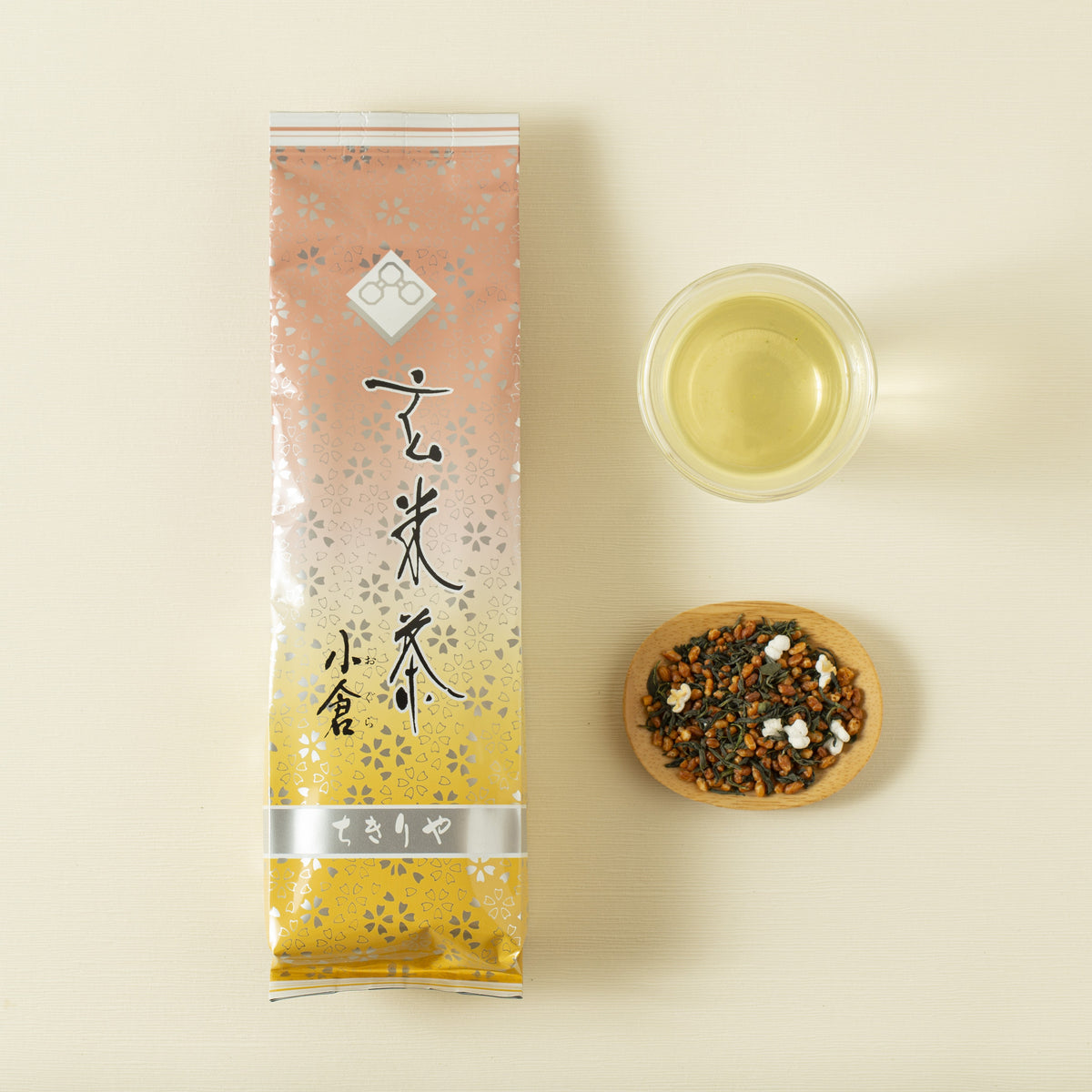 Gemaicha package with a cup of tea and a bowl of loose tea leaves on a beige background