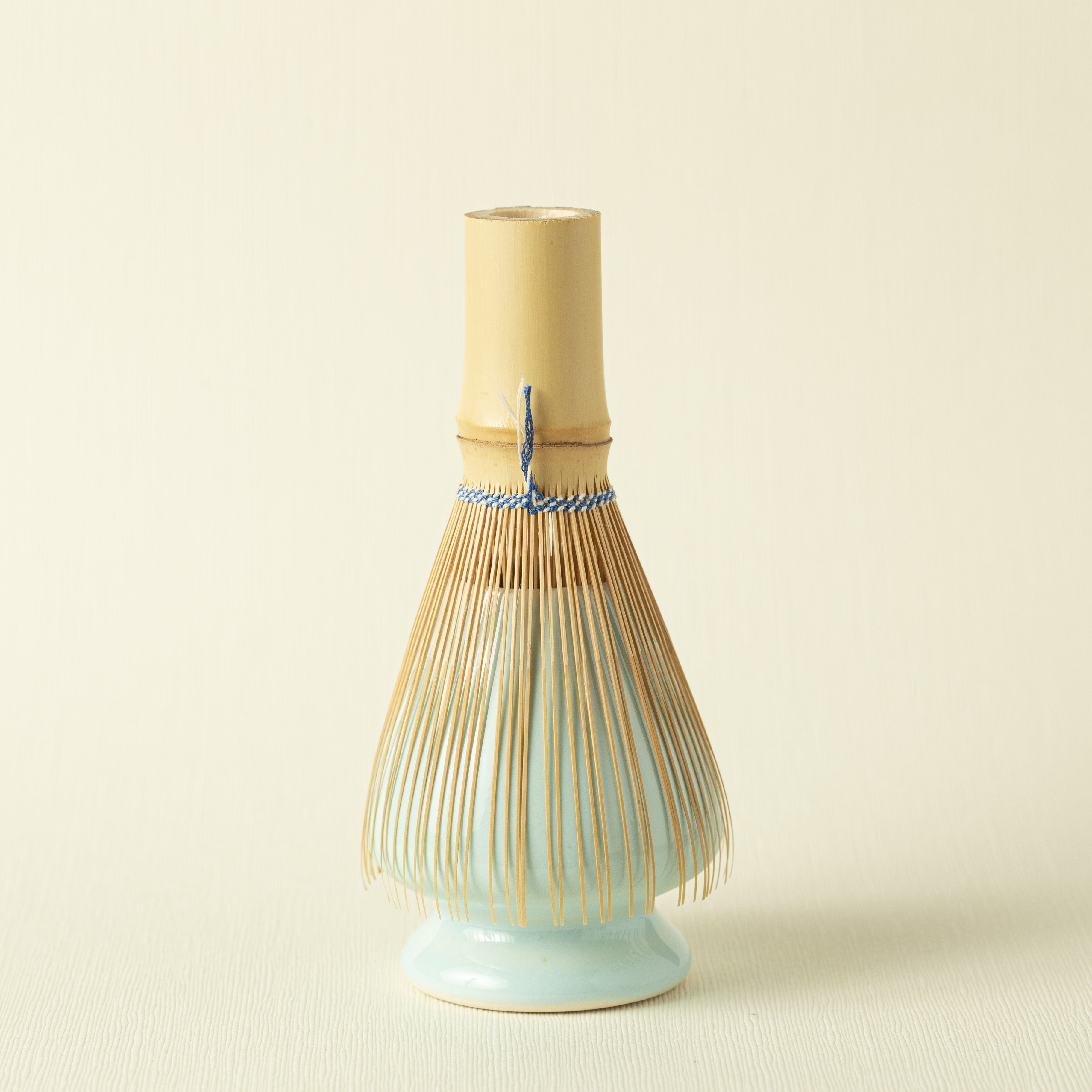 Ceramic blue whisk stand with bamboo whisk (chasen) on a beige background