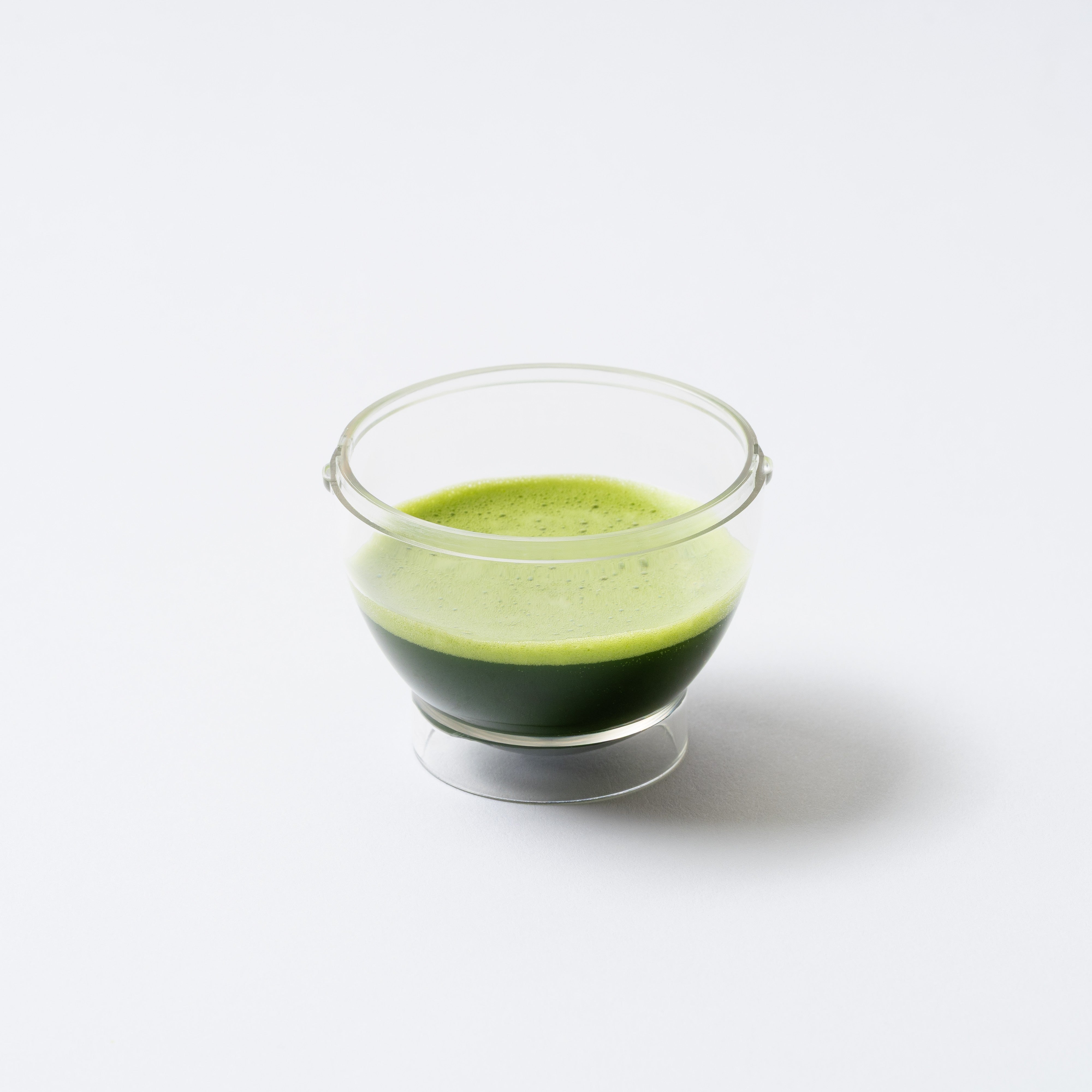 Clear glass bowl with green liquid on a white background