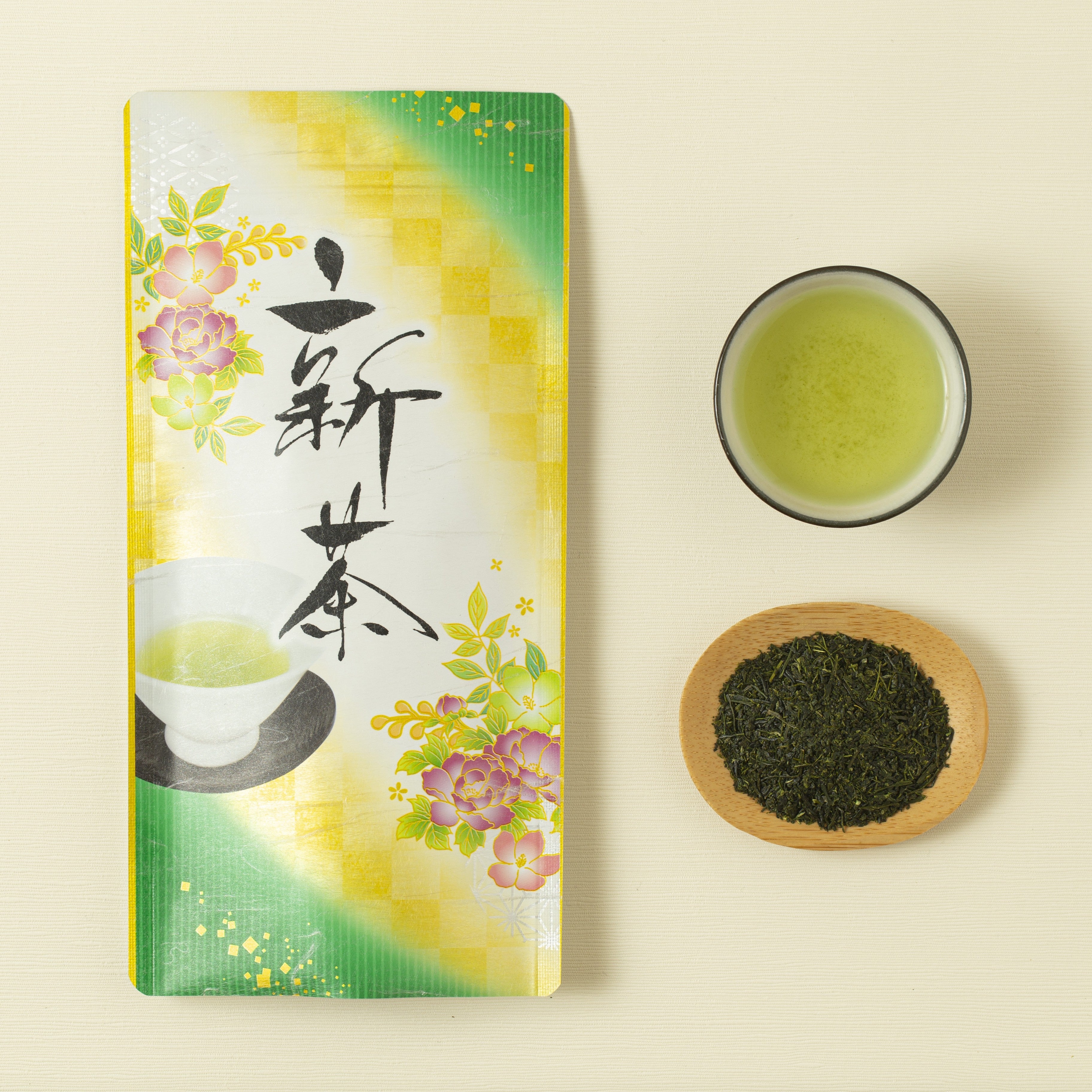 Packaging of green tea with a bowl of tea leaves and a cup on a beige background