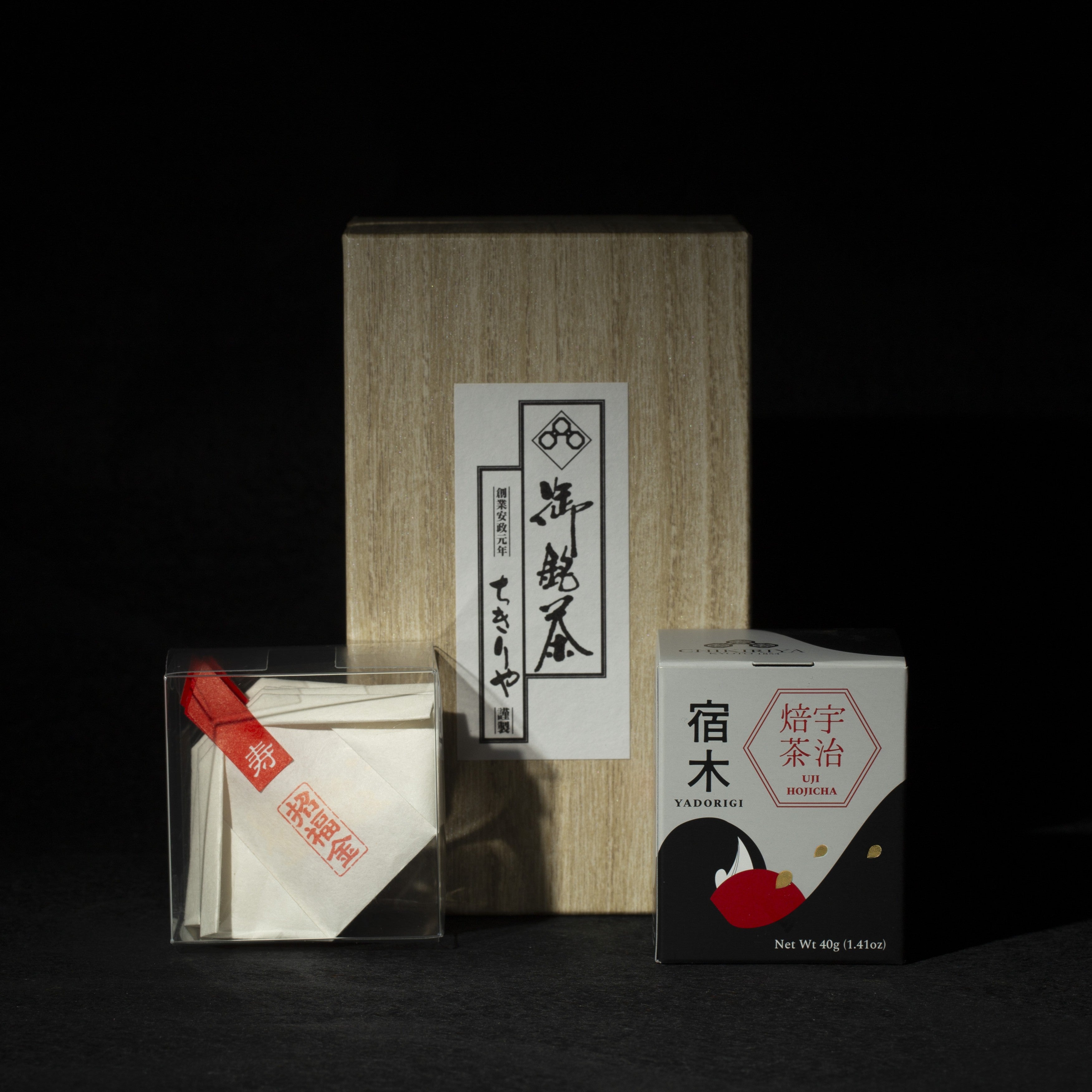Tea packaging with a wooden box and transparent container with gold edible glitter flakes, hojicha can on a dark background