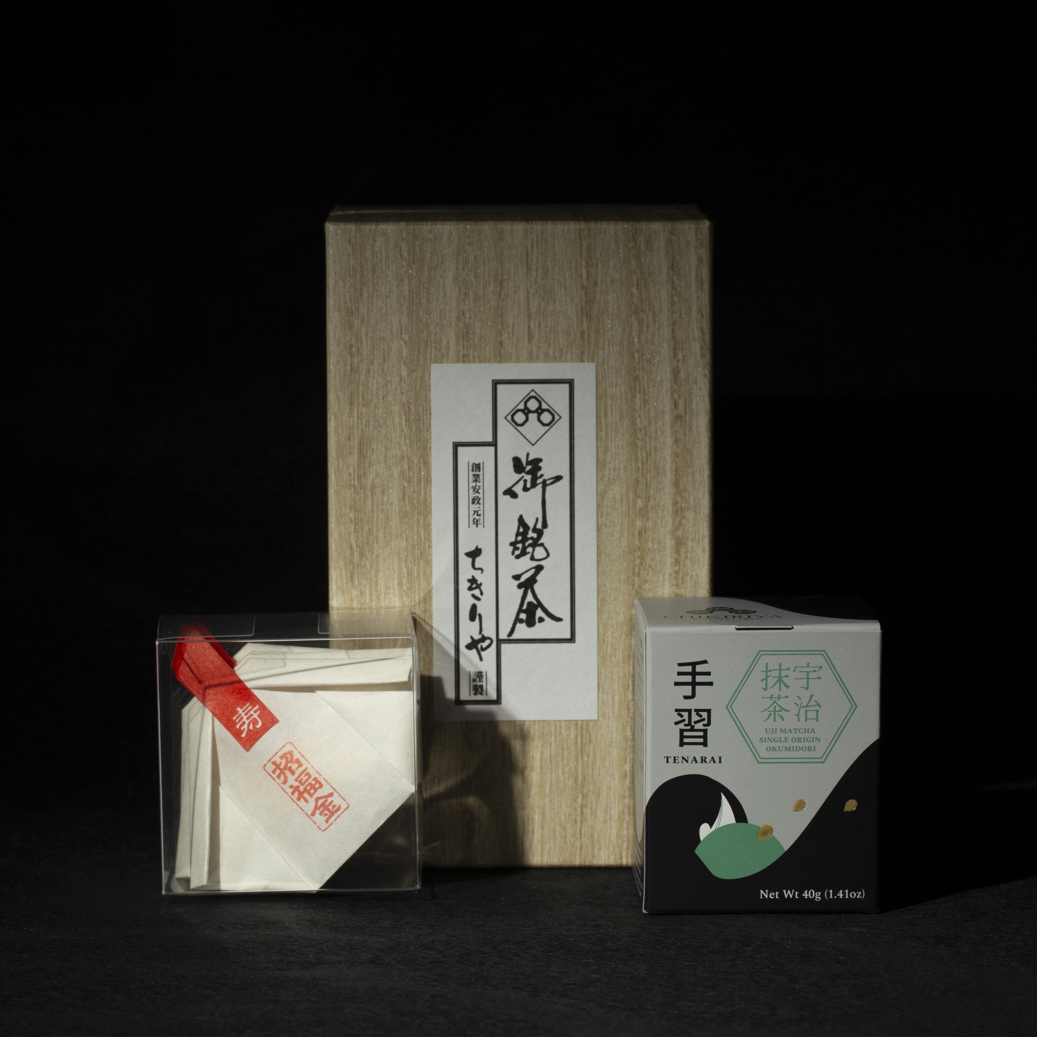 Tea packaging with a wooden box and transparent container with gold edible glitter flakes, matcha can on a dark background