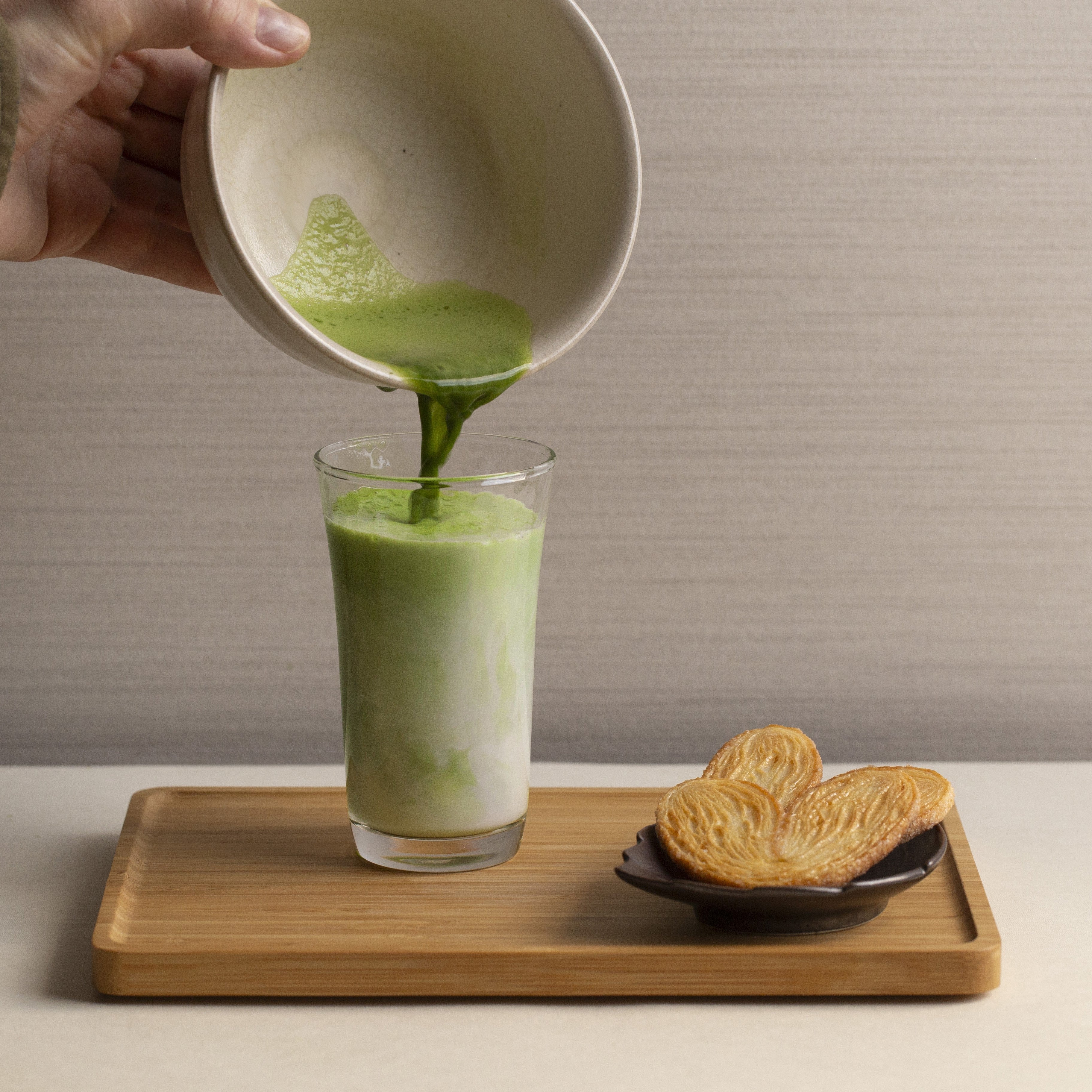 matcha poured into a glass of milk and biscuits on the side