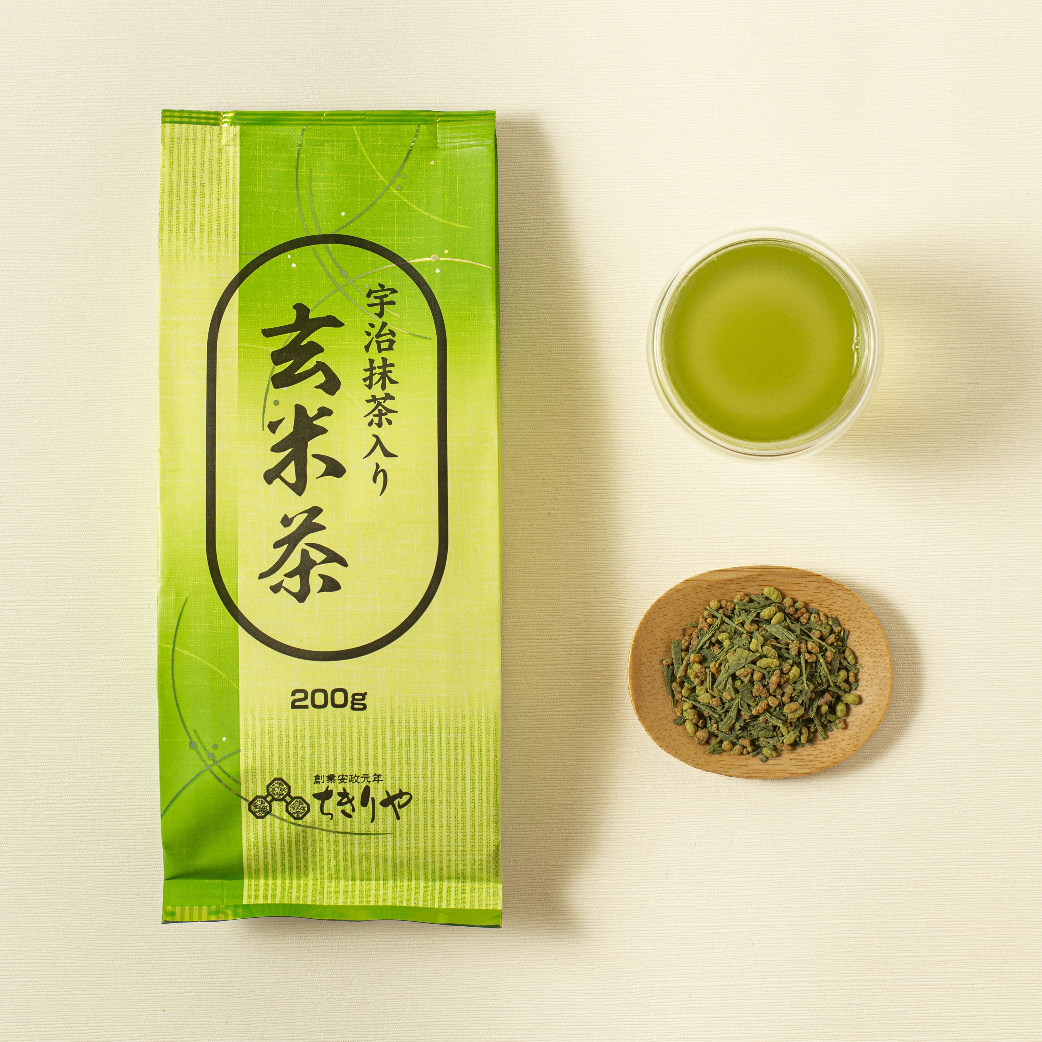 Green tea package with a cup of green tea and a bowl of tea leaves on a light background