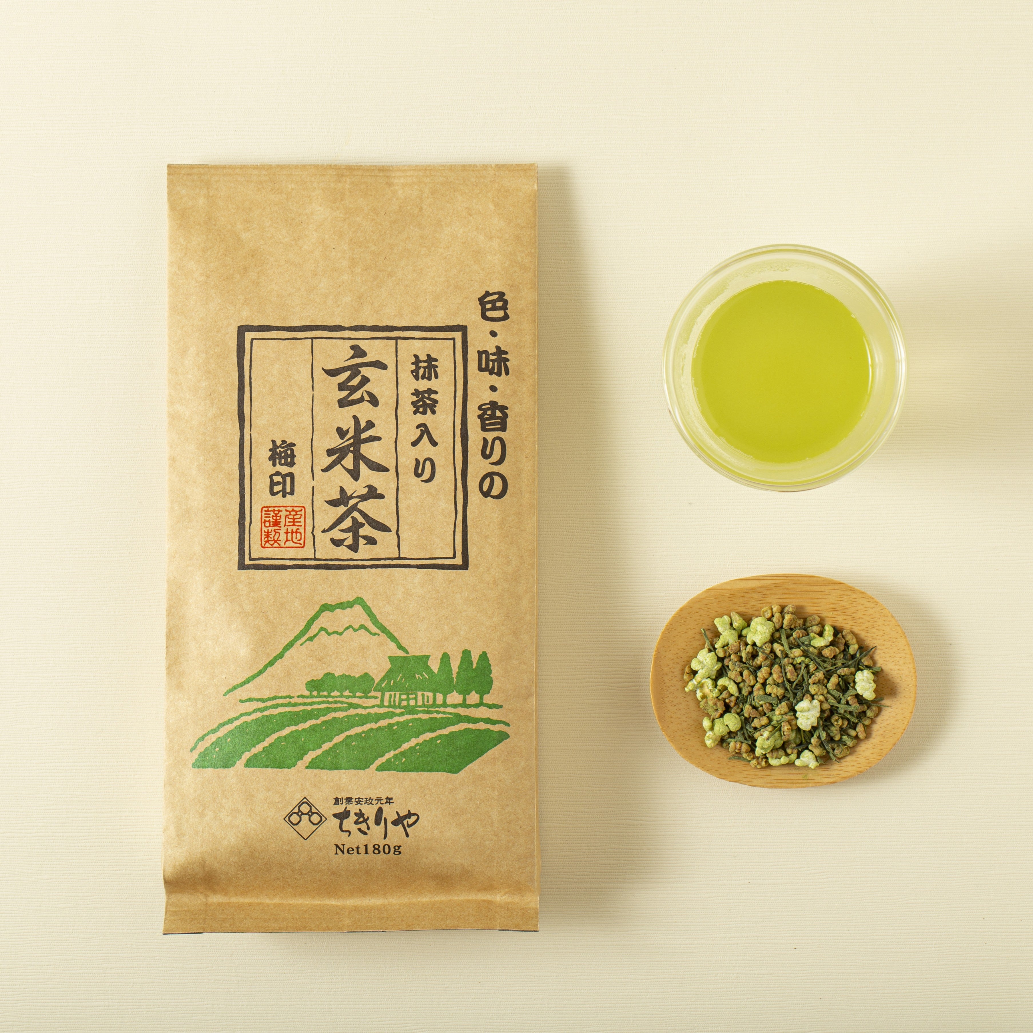 Genmaicha matcha package with a cup of green tea and a bowl of tea leaves on a beige background