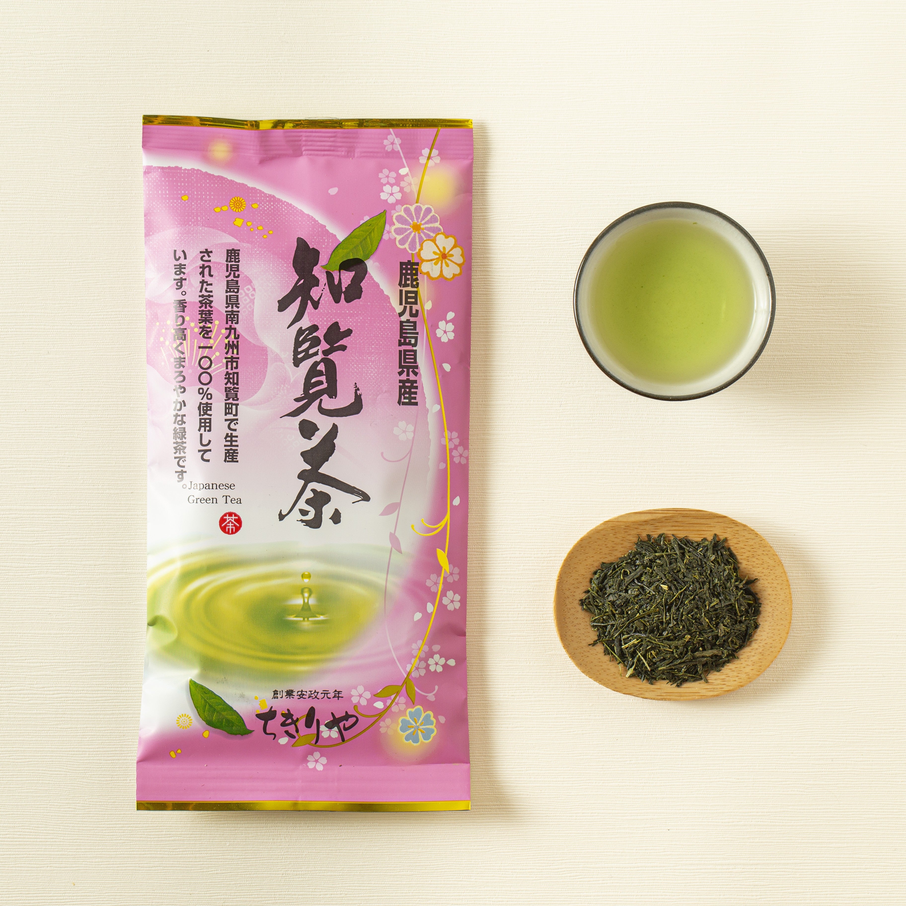 Tea package with a cup of green tea and a bowl of tea leaves on a light background