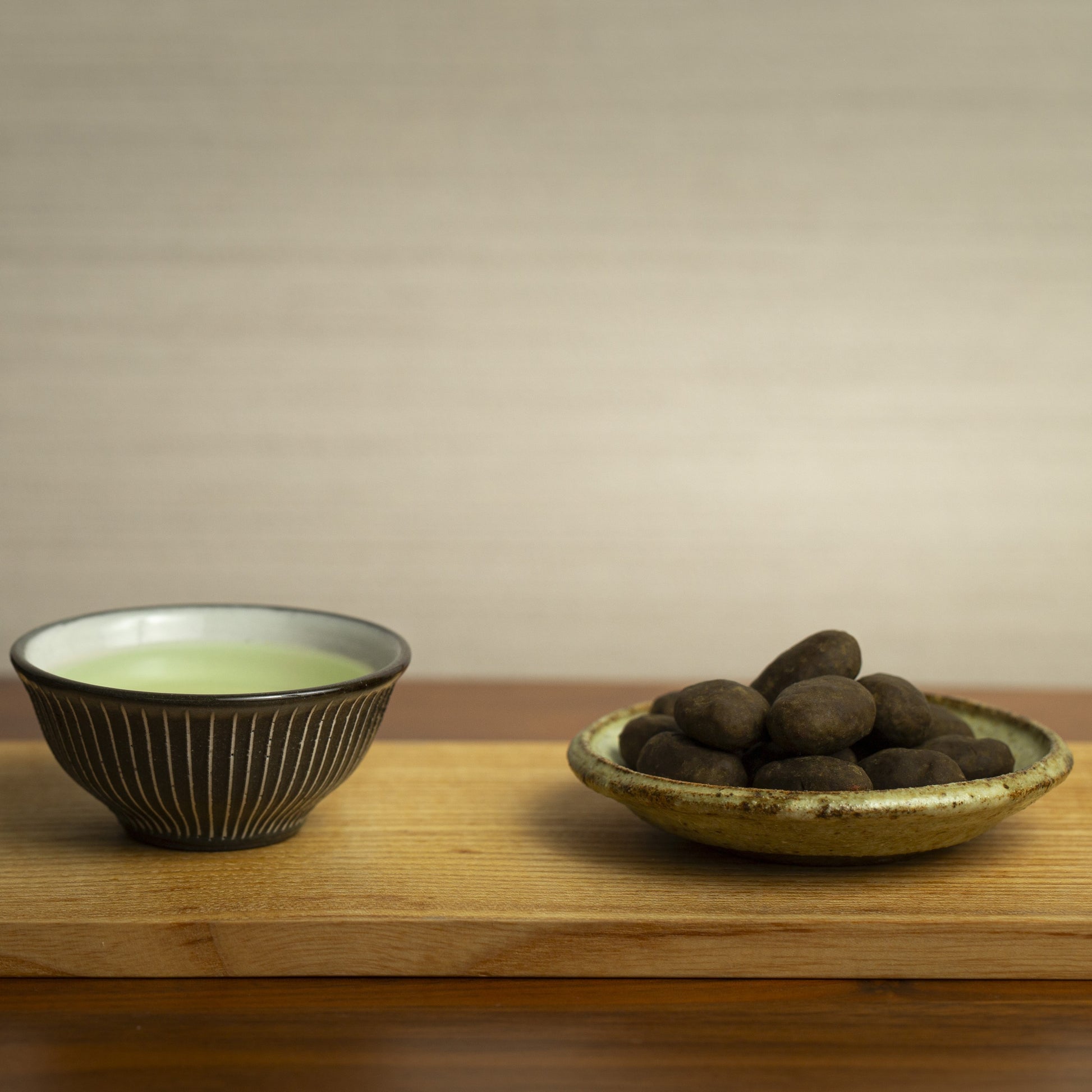 On left, japanese green tea. On right, hojicha almonds in a plate