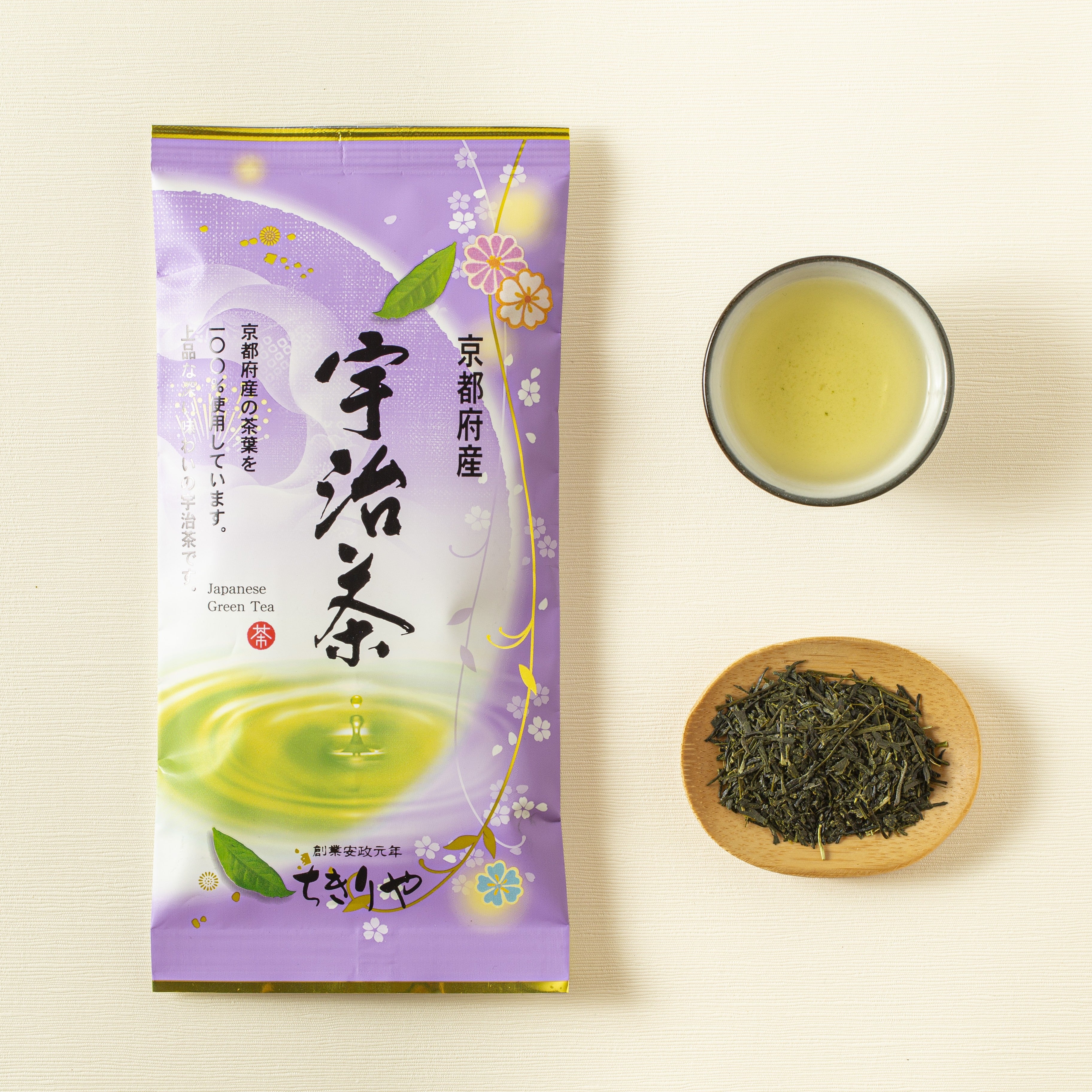 Tea packaging with a cup of green tea and a bowl of tea leaves on a light background