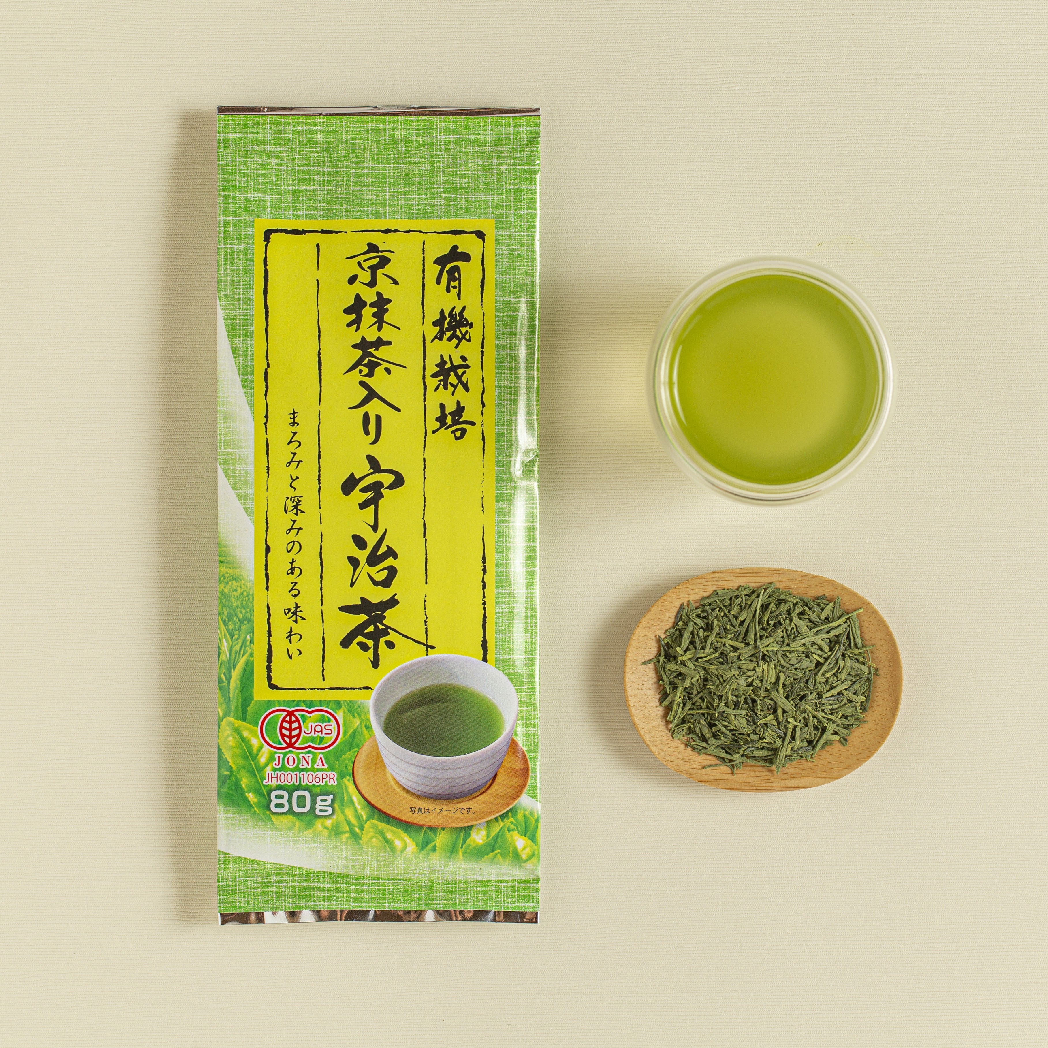 Tea package with a cup of green tea and a bowl of tea leaves on a beige background