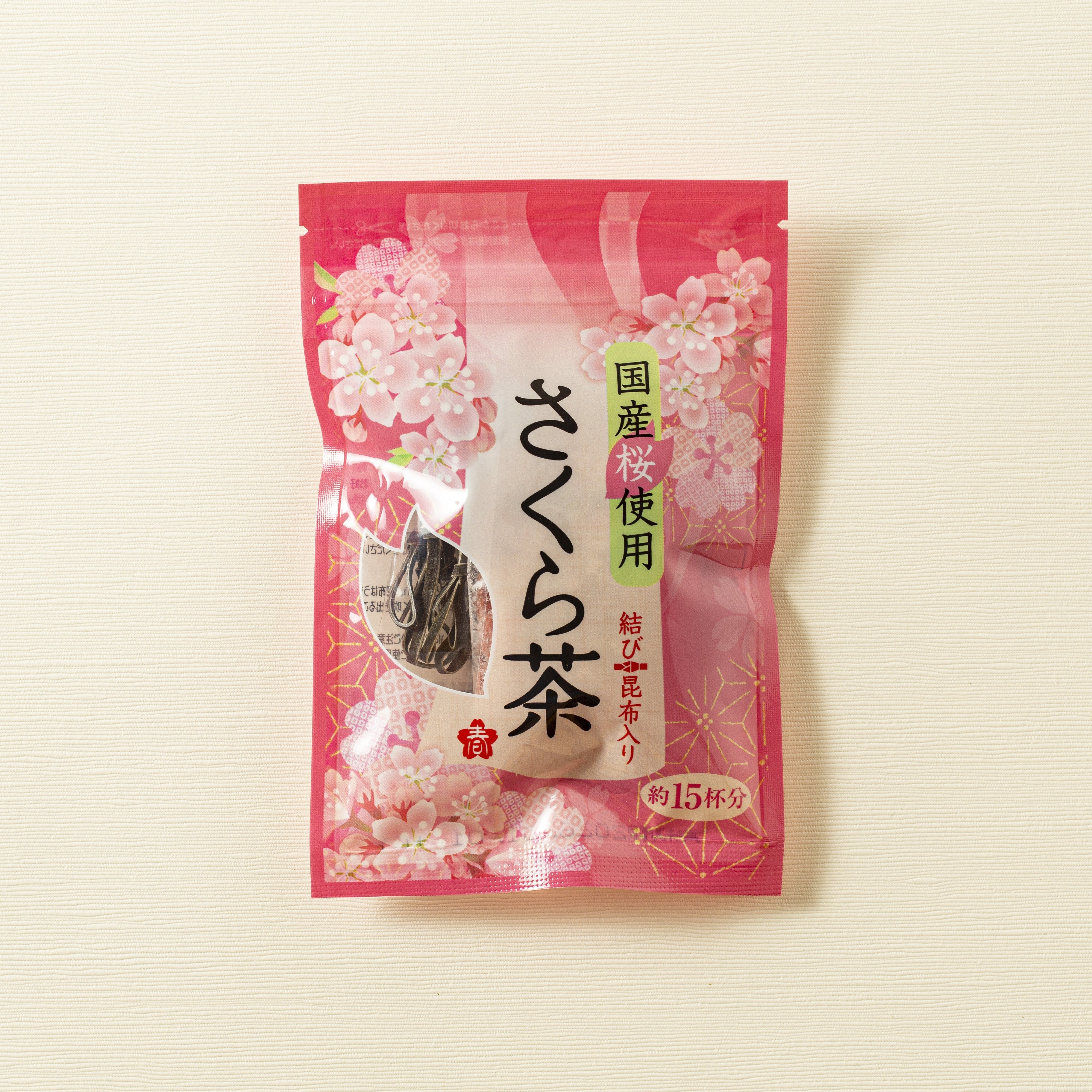Pink tea package with cherry blossom design on a beige background