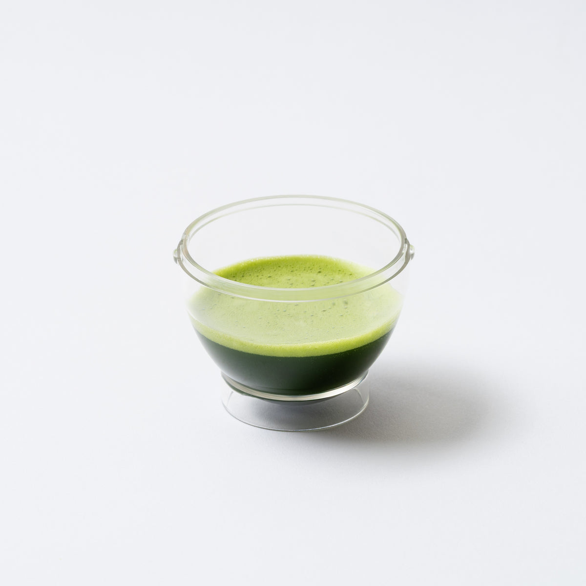 Clear glass bowl with green liquid on a white background