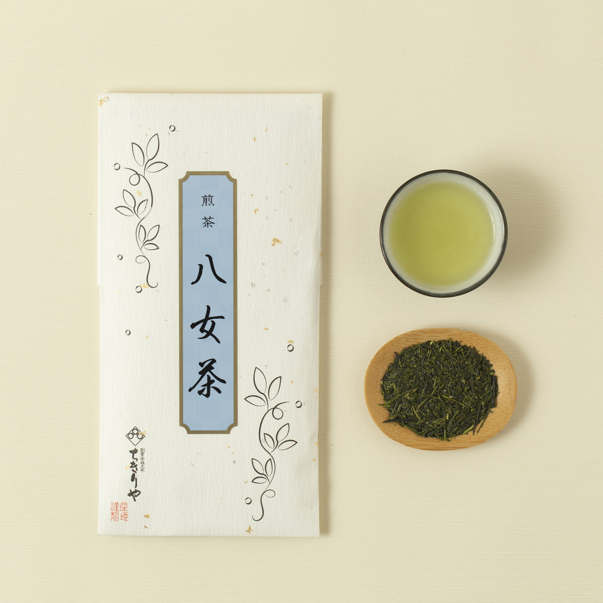 Tea packaging with a cup of green tea and a bowl of tea leaves on a beige background