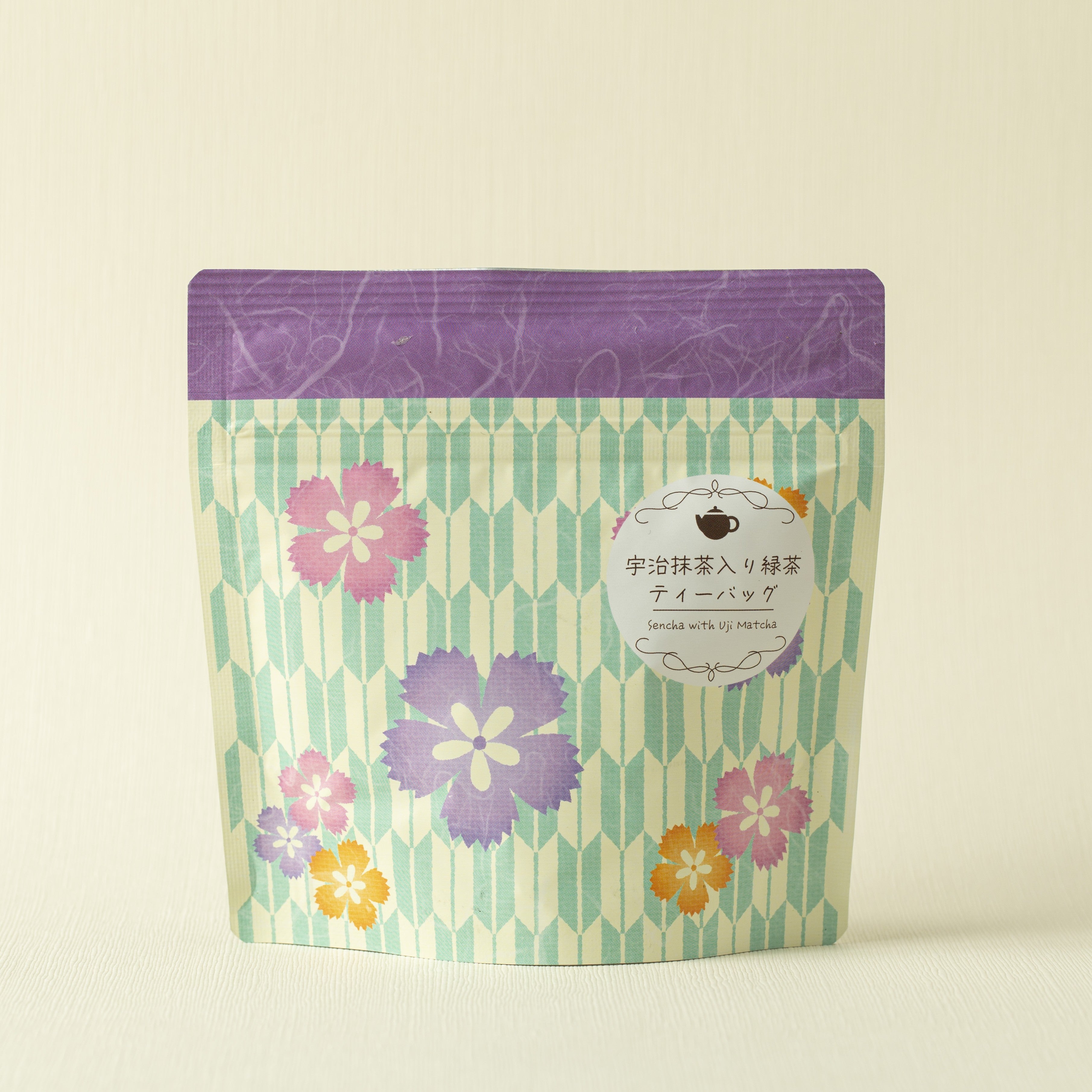 Tea bag package with floral design and purple label on a beige background
