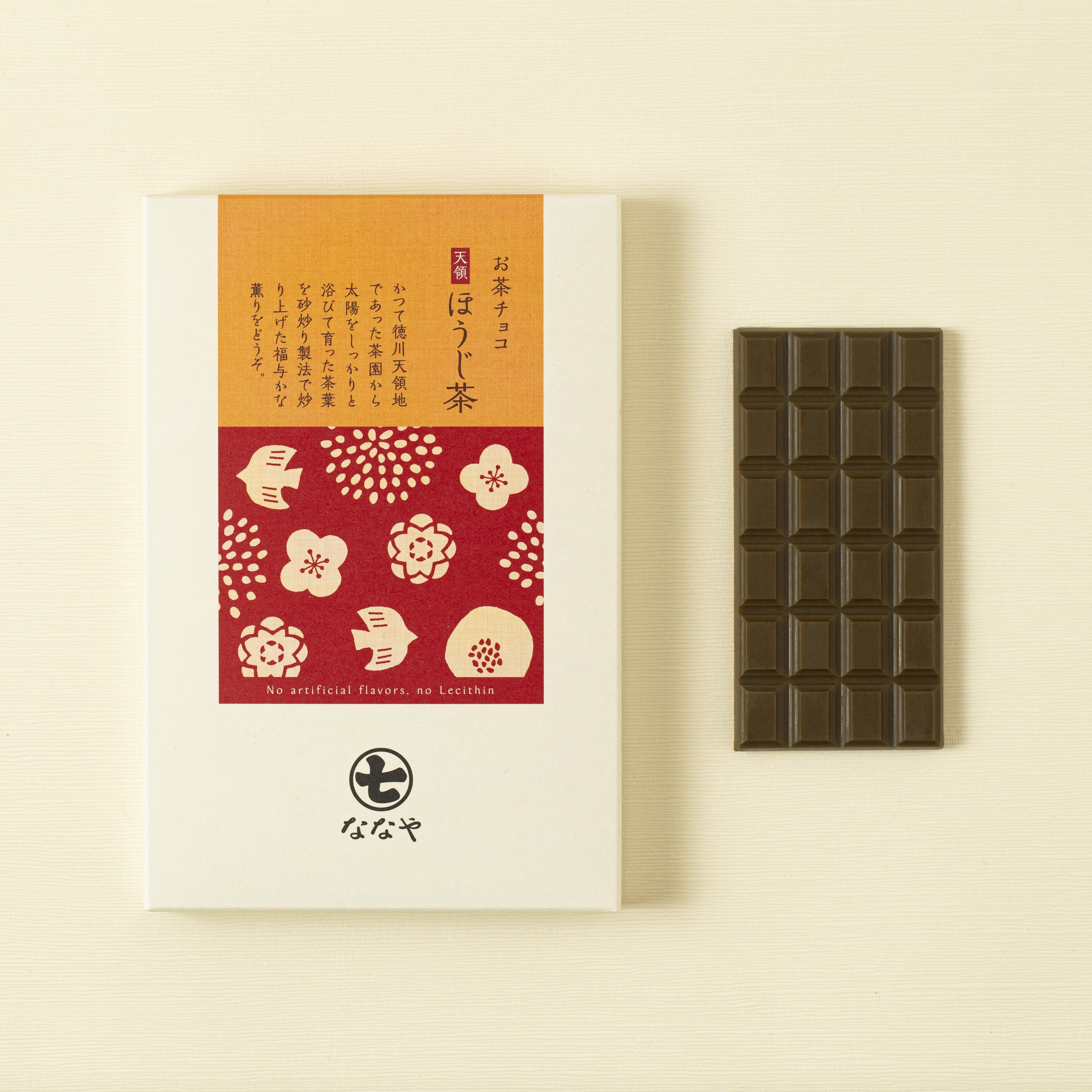 Hojicha chocolate bar and packaging with floral design on a beige background